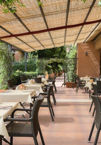 Ristorante all'aperto con tavoli apparecchiati sotto un pergolato.