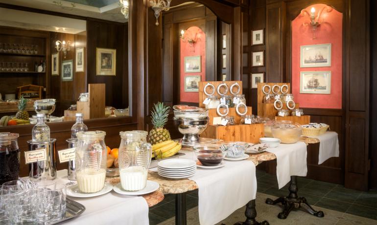 Buffet per colazione con frutta, cereali e bevande in un ambiente elegante.