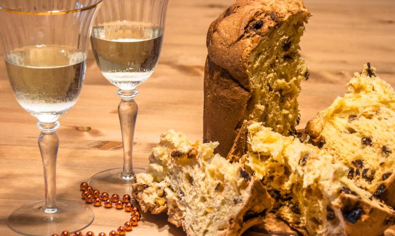Panettone e spumante su tavolo di legno, decorazione festiva.