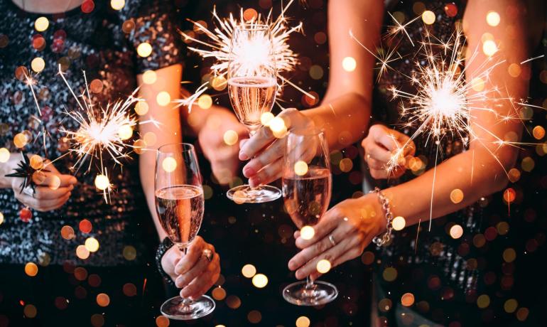Persone festeggiano con spumante e scintille.