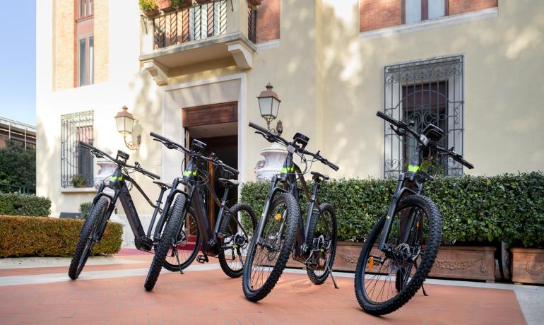 Cinque biciclette elettriche nere davanti a un edificio elegante.