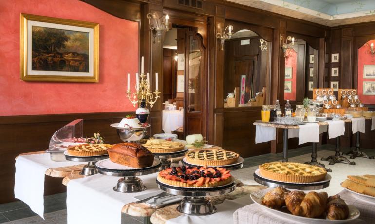 Buffet con torte, croissant e bevande in un'elegante sala.